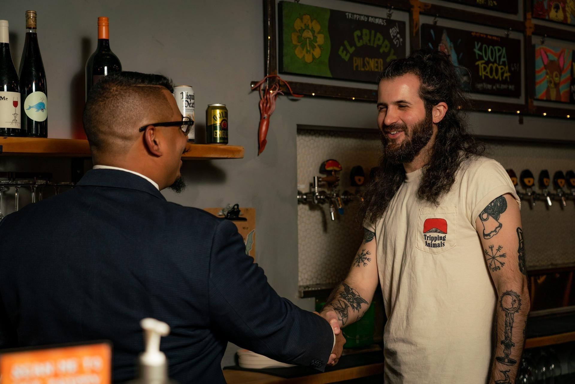 Reynaldo Martinez of RAM Law & Title shaking hands with a small-business client at their Miami brewery